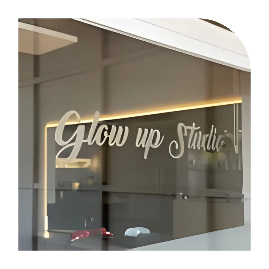 Rótulo dorado de Glow Up Studio en el cristal de la entrada